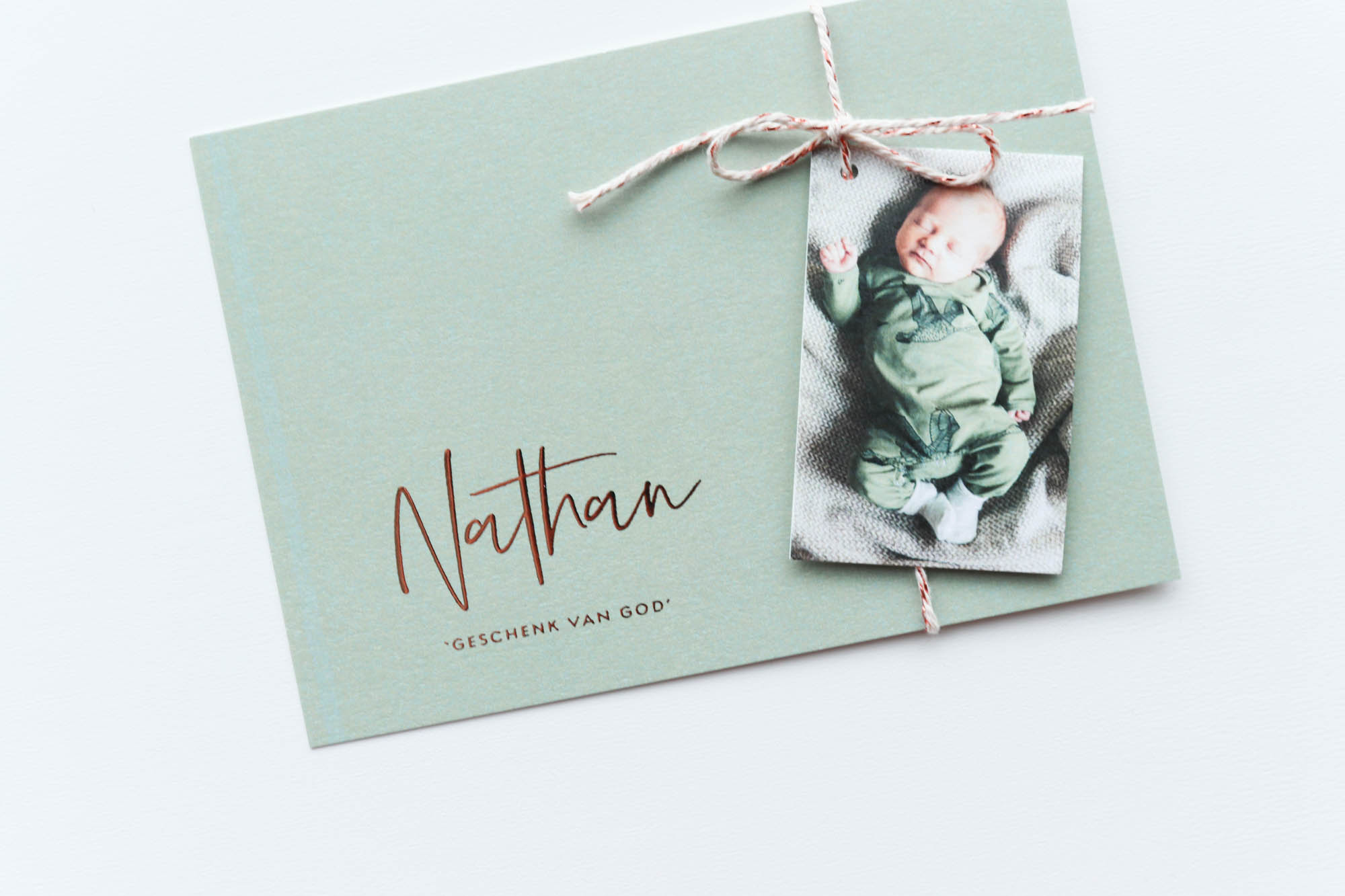 Een groen geboortekaartje met koperfolie letters en een fotolabel